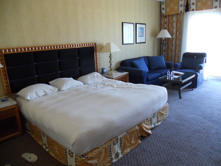 Habitación de hotel con cama y zona de estar azul